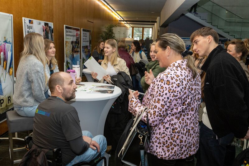 Personen stehen um einen runden Stehtisch.