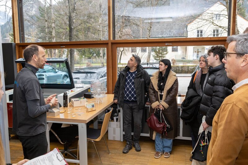 Personen stehen in einem Raum und blicken auf die Geräte.