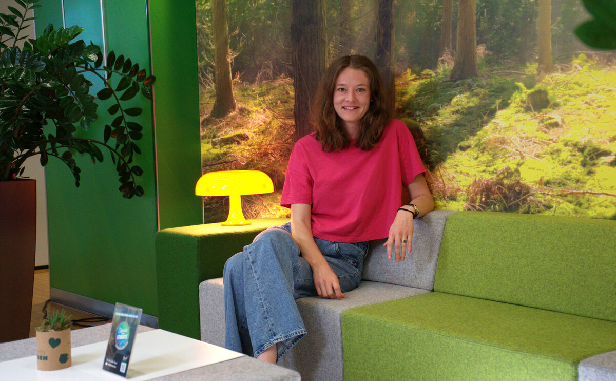 Person sitzt auf einem grünen Sofa und blickt direkt in die Kamera.