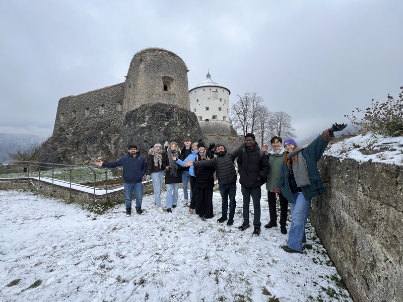 Studierende stehen im Freien vor einem Turm.