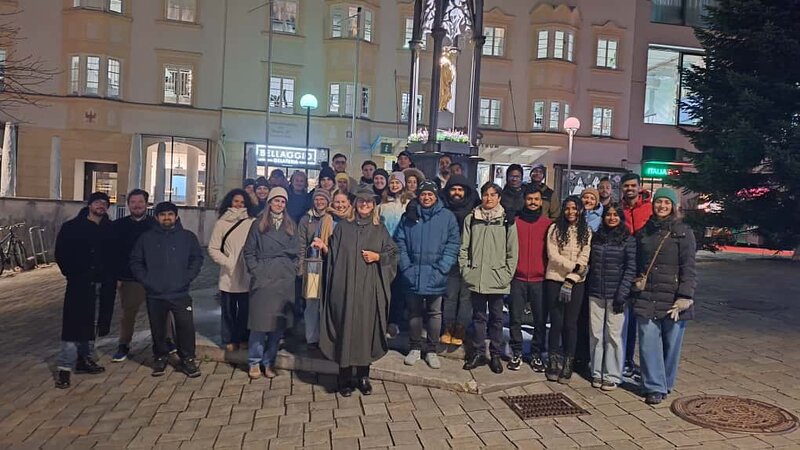 Personen stehen vor einem Brunnen zusammen.