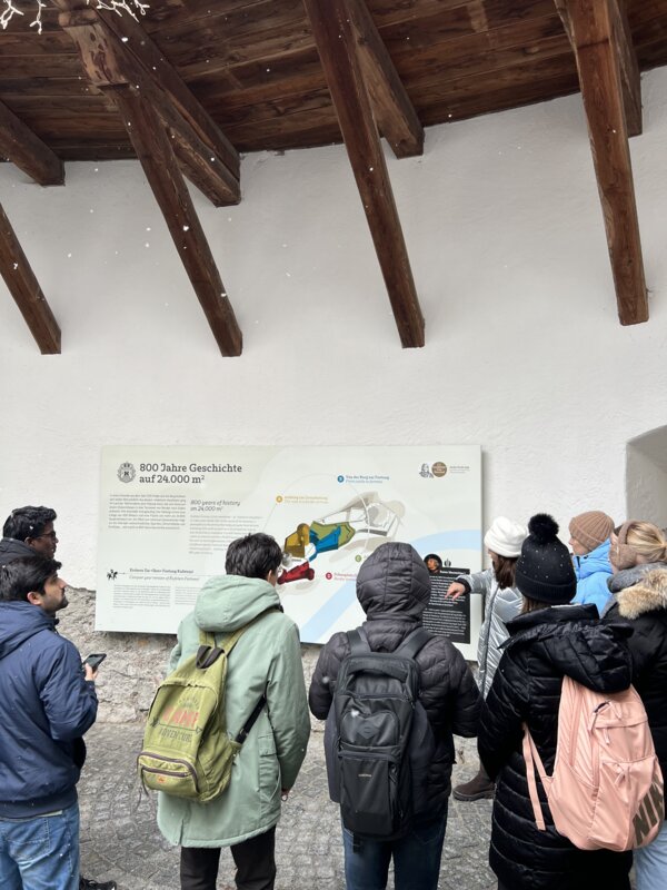 Teilnehmer:innen stehen vor einer Infotafel im Inneren der Festung.