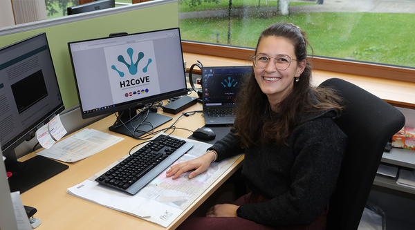 Franziska Boroviczény, wissenschaftliche Mitarbeiterin am Institut für Sustain & Estate, sitzt an einem Schreibtisch und blickt in die Kamera. | © FH Kufstein Tirol