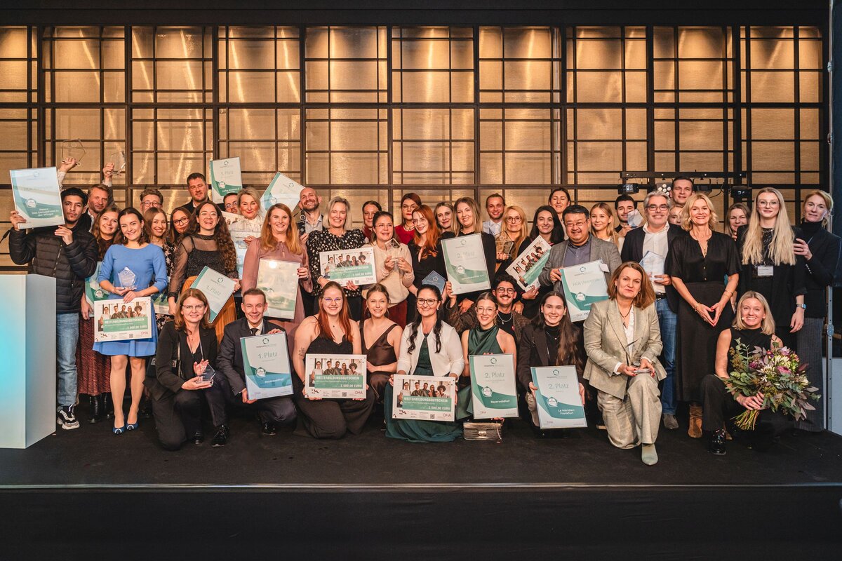 Festlich gekleidete Personen stehen auf einer Bühne und halten ihre Preise in den Händen.