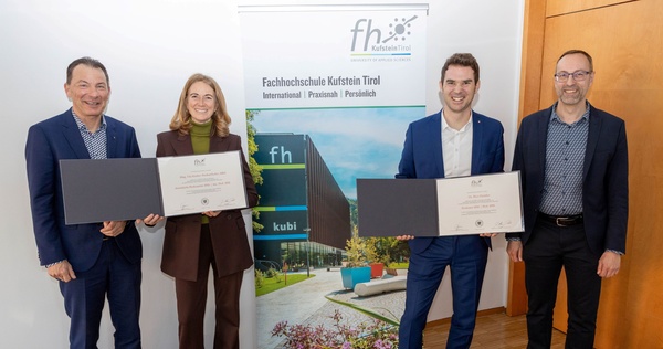 Vier Personen stehen vor einem Roll-up und zwei davon halten eine Urkunde in die Kamera. | © FH Kufstein Tirol