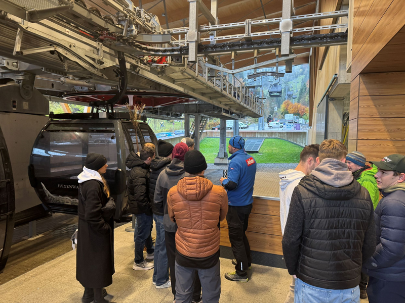 Personen stehen neben einer Gondel.