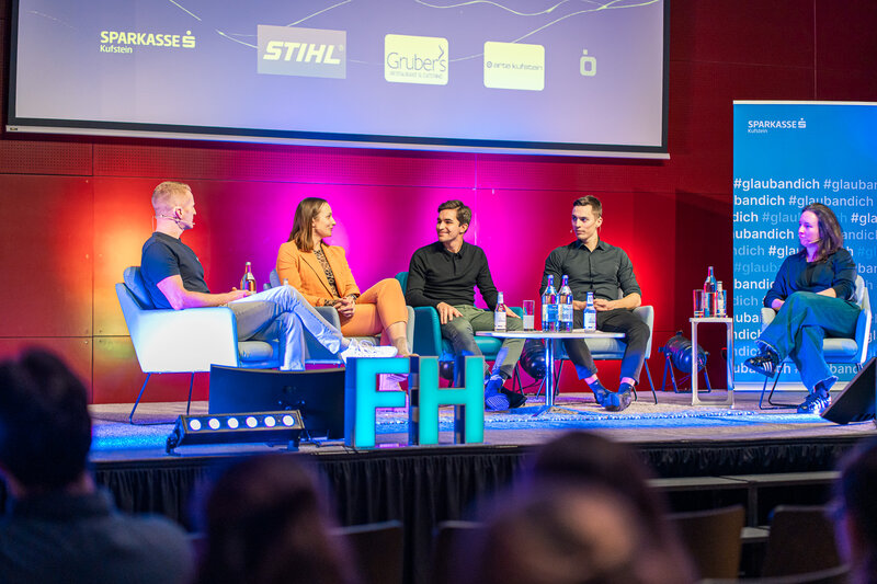 Personen sitzen auf einer Bühne.