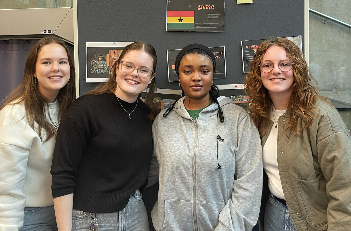 Vier Personen stehen vor einer Pinnwand als Gruppe zusammen.