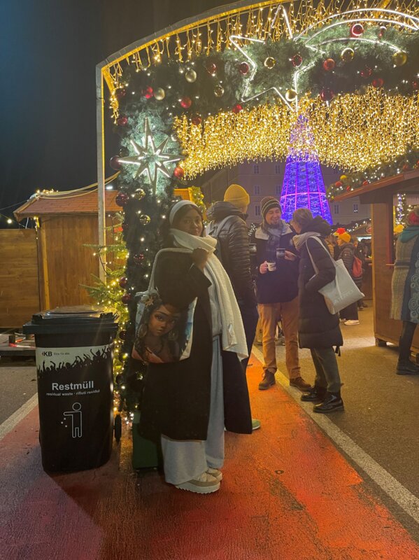 Esther steht vor einem leuchtenden Bogen vor einem roten Läufer auf dem Weihnachtsmarkt.