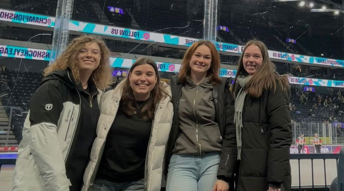 Vier Personen stehen in einem Eishockey-Stadion.