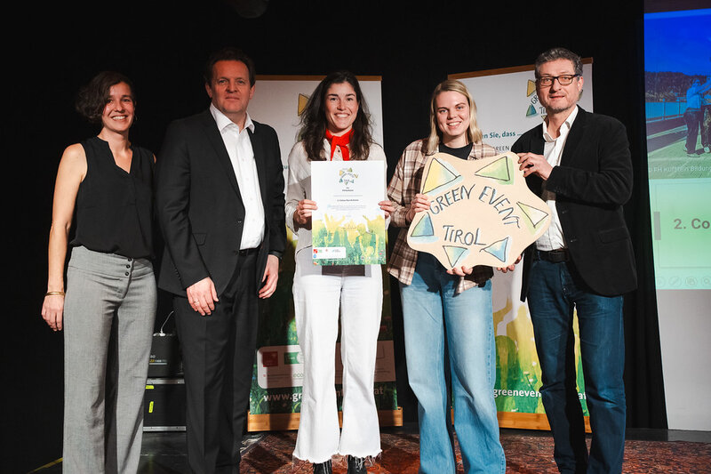 Personen stehen auf einer Bühne nebeneinander und halten ihre Auszeichnungen in die Kamera.