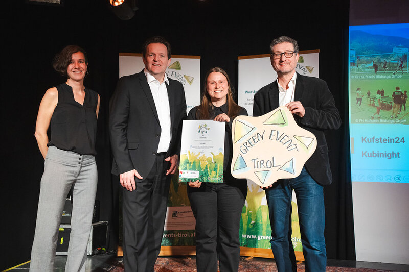 Personen stehen auf einer Bühne nebeneinander und halten ihre Auszeichnungen in die Kamera.