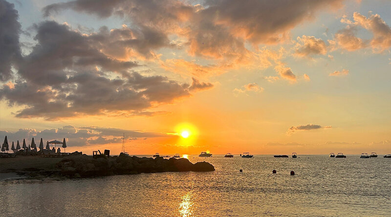 Blick vom Strand über das Meer zur untergehenden Sonne.