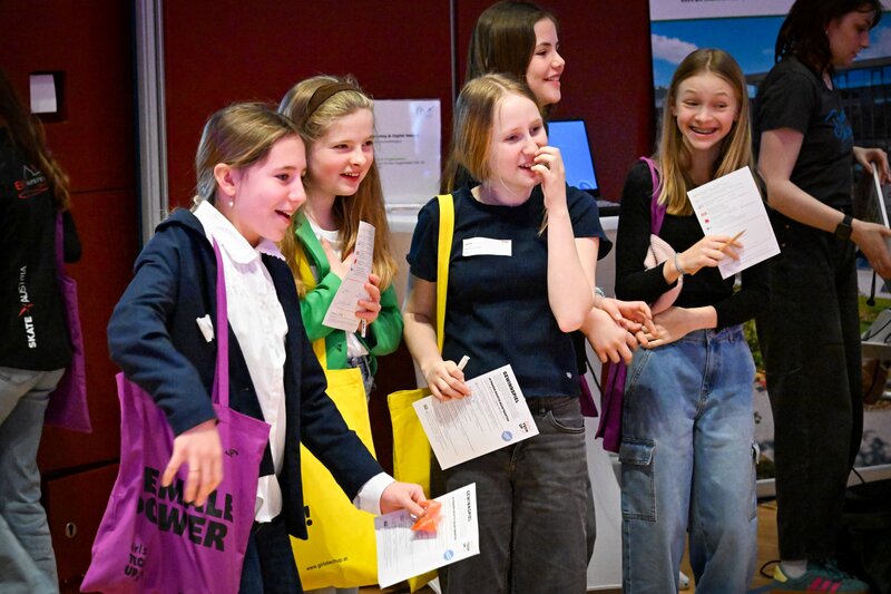 Mädchen stehen nebeneinander mit bunten Stofftaschen über ihren Schultern und lachen.