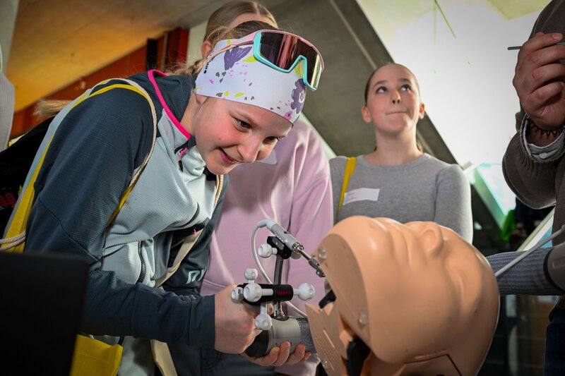 Ein Mädchen aktiv bei einer Mitmachstation und einer Menschenpuppe.