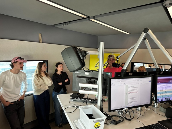 Studierende stehen im Radiostudio zwischen Mikrofonen, Monitoren und Studiotechnik und hören den Erklärungen eines Radioprofis zu. | © FH Kufstein Tirol