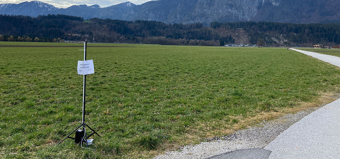 LoRaWAN-Gateway-Positionierung-Daten-Erfassung-Freifeld | © FH Kufstein Tirol LoRaWAN-Gateway auf einem Stativ im offenen Feld zur Erfassung von Positionsdaten mit Bergen im Hintergrund. | © FH Kufstein Tirol