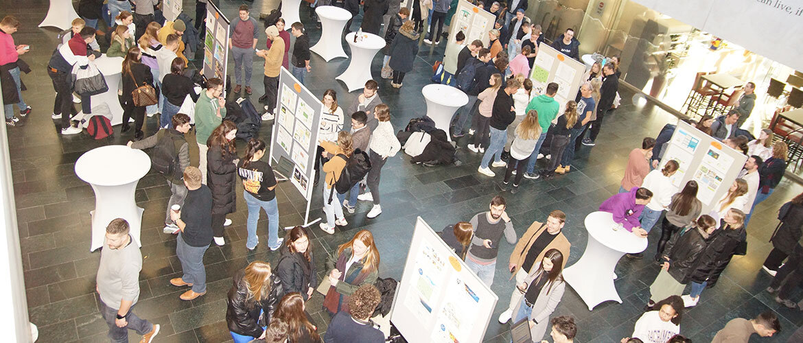 Studierende-Poster-Ausstellung-FH-Kufstein-Tirol-Aula Studierende in der Aula der FH Kufstein Tirol bei der Posterausstellung während einer akademischen Ausstellung.