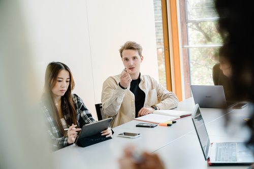 Meetingroom_Besprechung_2 | © FH Kufstein Tirol Drei Personen sitzen an einem Tisch, und ein Mann dieser Gruppe zeigt mit seinem Stift in die Richtung der Kamera, wo sich ein Whiteboard befindet. | © FH Kufstein Tirol