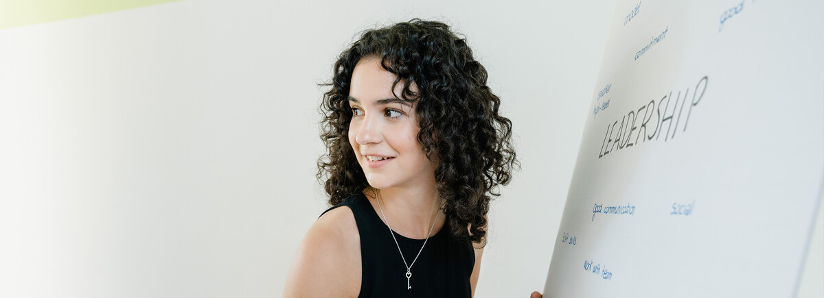 Über_die_International_Business_School_Sektion_2 | © FH Kufstein Tirol Eine Frau hört einer anderen Person zu, und schreibt Notizen auf ein Whiteboard. | © FH Kufstein Tirol
