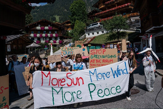 Eine friedays4Future Demo in dem alpenländischen Dorf Alpbach, ein großes Transparent im Vordergrund auf dem steht:" More Sun, More Wind, More Peace"
