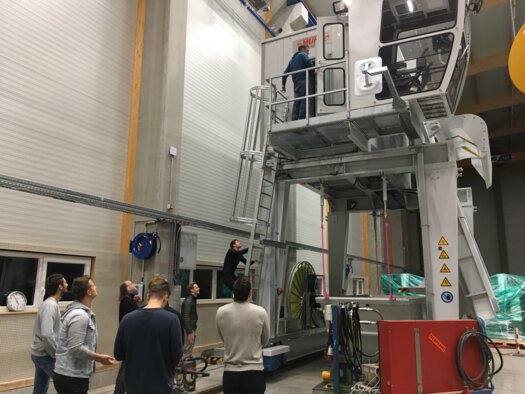 Studierende erklimmen einen Rechenreiniger im Werk der Firma Muhr in Brannenburg