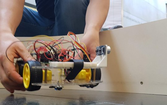 Ein Student setzt sein RobotCar auf die Rennstrecke