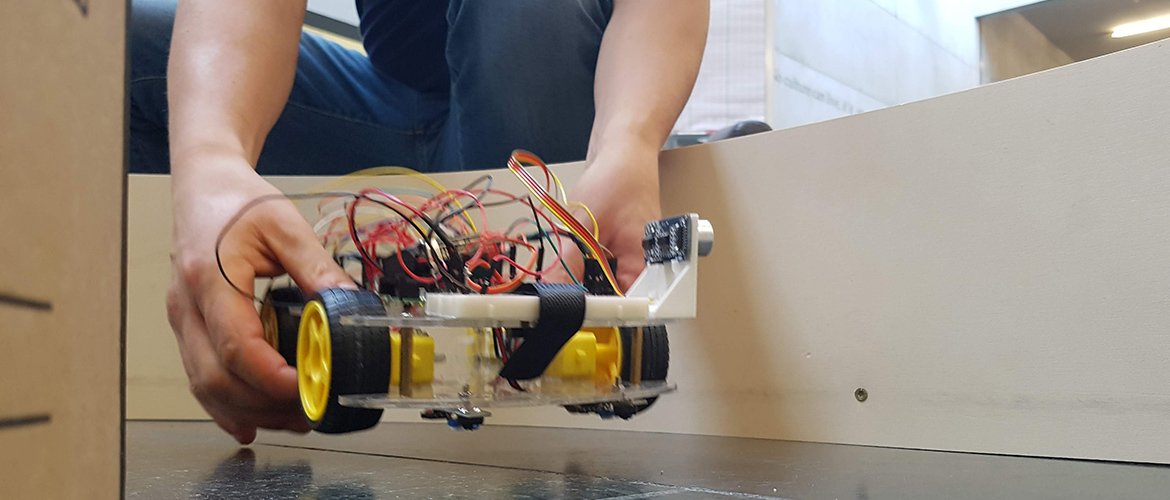 Ein Student setzt sein RobotCar auf die Rennstrecke