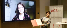 Aufnahme der Verleihung: Lena Reil (auf einem Bildscjirm eingeblendet) davor das Vorstandsmitglied Androsch-Holzer mit der Urkunde in der Hand